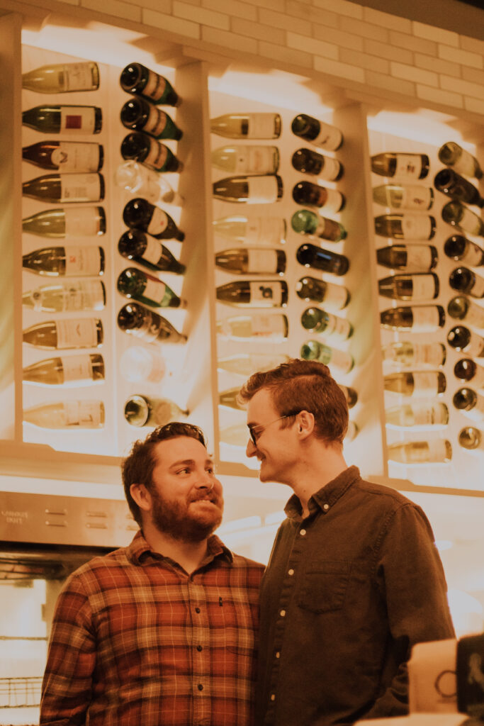 A gay couple smiling at each other inside of a restaurant