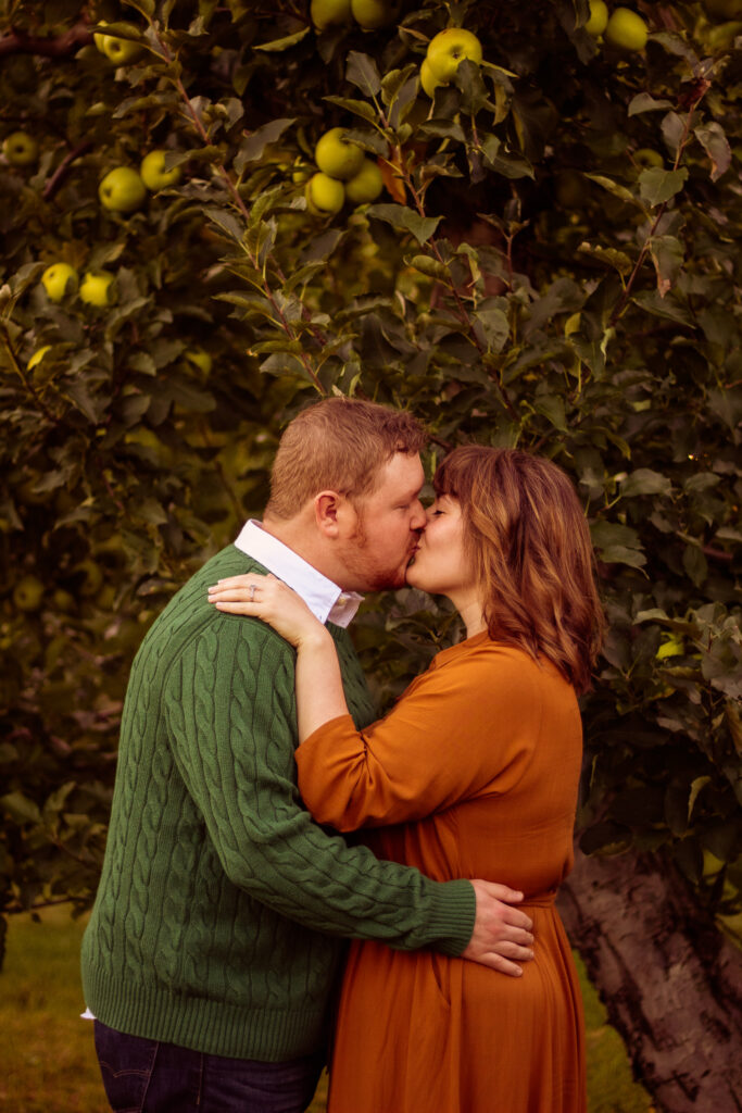 A couple kissing in an apple orchard